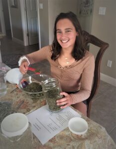 A girl putting herbs in a jar